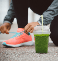 Detox smoothie drink and running footwear close up  City outdoor workout and fitness healthy nutrition concept   Female athlete tying sport shoes laces before training 