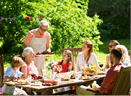 leisure, holidays and people concept - happy family having festive dinner or barbecue party at summer garden