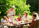 leisure, holidays and people concept - happy family having festive dinner or barbecue party at summer garden