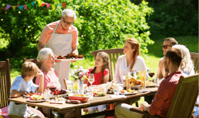 leisure, holidays and people concept - happy family having festive dinner or barbecue party at summer garden