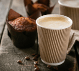 Coffee to go with muffin on wood background, copy space