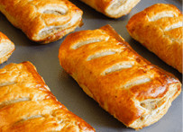 Freshly baked sausage rolls made with puff pastry fresh out of the oven cooling on a tray