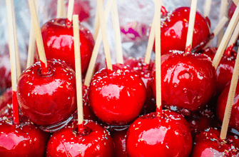 Sweet glazed red toffee candy apples on sticks for sale on farmer market or country fair 