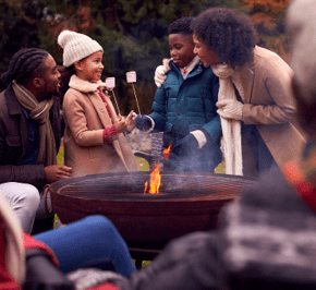 Multi-Generation Family Having Fun Toasting Marshmallows In Autumn Garden Together