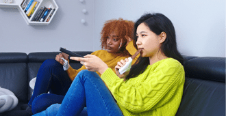 Two women lesbian couple watching television and eating chocolates  High quality photo