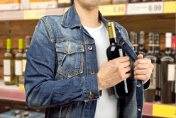 man in a supermarket stealing a bottle of champagne